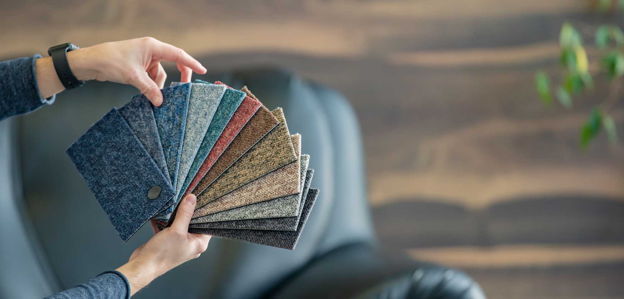 The man selects a new cover for the sofa from the color card sampler